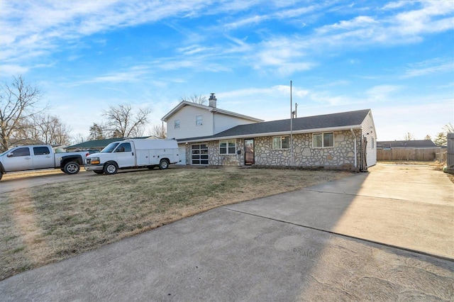 view of front of house with stone siding, fence, and a front yard