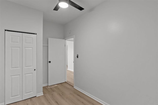 unfurnished bedroom with light wood-type flooring, a closet, and ceiling fan