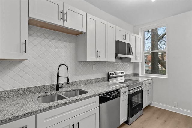 kitchen featuring white cabinets, sink, light stone countertops, and stainless steel appliances