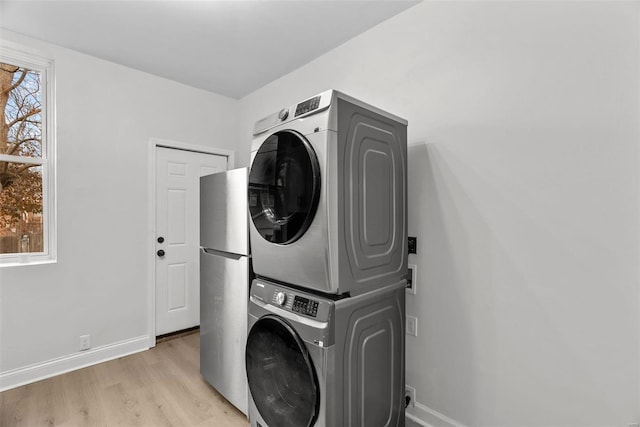 laundry room featuring stacked washer and dryer and light hardwood / wood-style floors