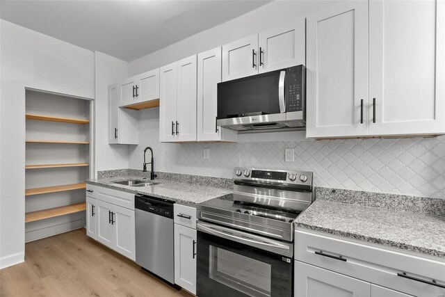 kitchen featuring white cabinets, appliances with stainless steel finishes, light wood-type flooring, and sink