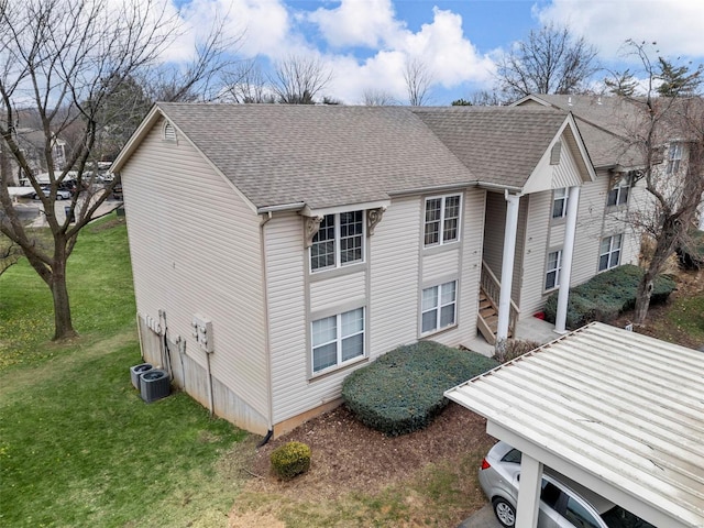 view of side of home with a lawn, cooling unit, and a carport