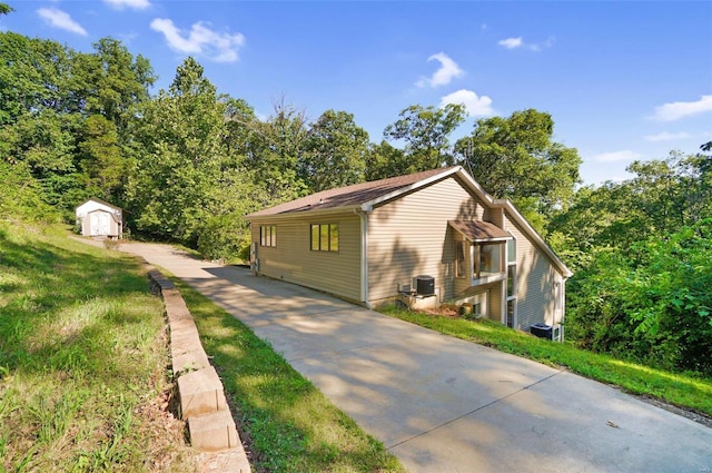 view of property exterior featuring central AC and a storage unit