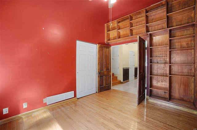 empty room featuring a towering ceiling and light wood-type flooring