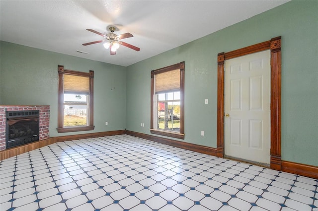 unfurnished living room with ceiling fan and a brick fireplace