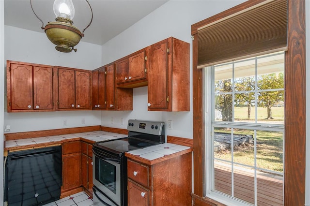 kitchen featuring tile countertops, stainless steel range with electric stovetop, and black dishwasher