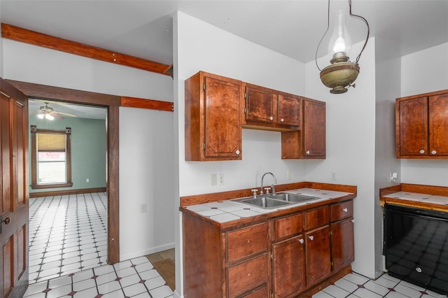 kitchen featuring ceiling fan, tile counters, decorative light fixtures, and sink