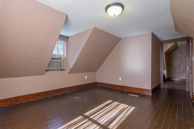 additional living space with dark hardwood / wood-style flooring, cooling unit, and lofted ceiling