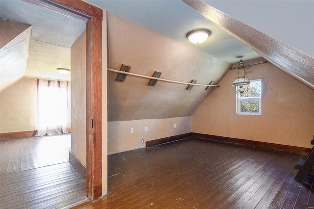 additional living space with dark wood-type flooring and vaulted ceiling