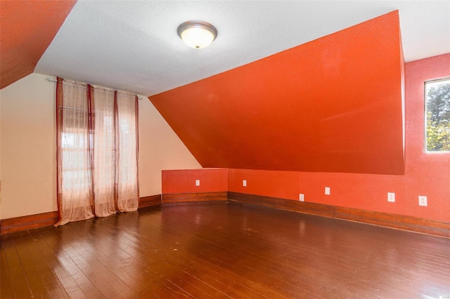 additional living space with vaulted ceiling, wood-type flooring, and a textured ceiling