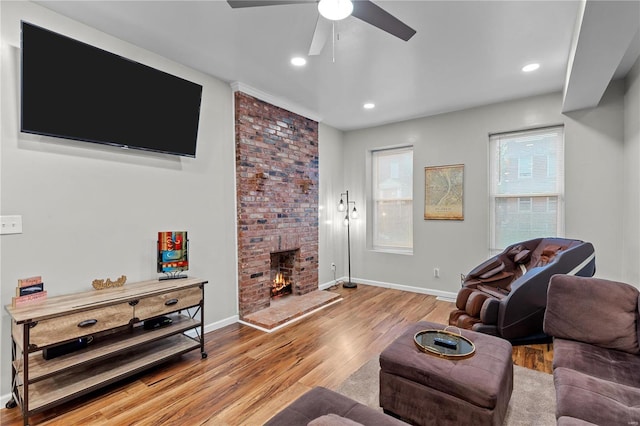 living room with ceiling fan, a fireplace, and light hardwood / wood-style flooring