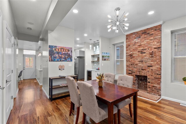 dining area featuring a fireplace, hardwood / wood-style flooring, wine cooler, and a chandelier