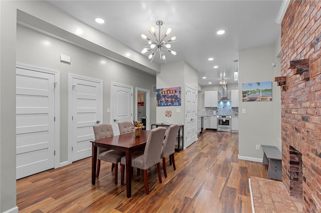 dining area with wood-type flooring, an inviting chandelier, and a brick fireplace