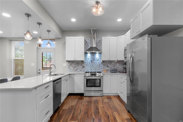 kitchen with sink, wall chimney exhaust hood, stainless steel appliances, backsplash, and white cabinets