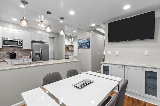 kitchen featuring pendant lighting, sink, a breakfast bar area, white cabinetry, and stainless steel appliances