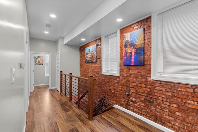 corridor featuring hardwood / wood-style flooring and brick wall