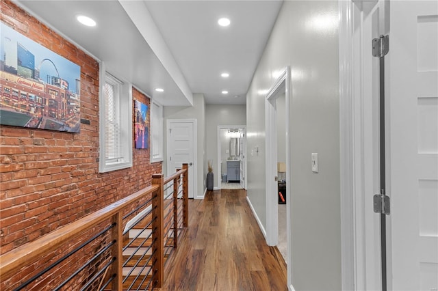 hall with dark hardwood / wood-style floors and brick wall