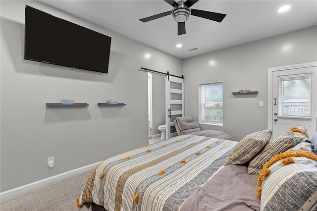 bedroom with carpet, a barn door, ceiling fan, and connected bathroom