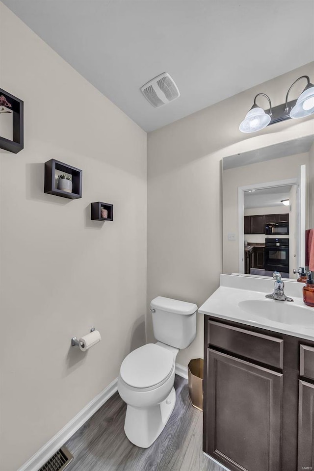 bathroom featuring vanity, hardwood / wood-style flooring, and toilet