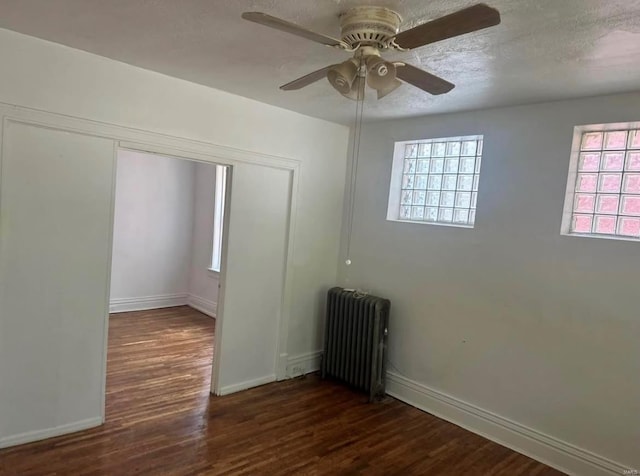 unfurnished room with ceiling fan, dark hardwood / wood-style flooring, and radiator