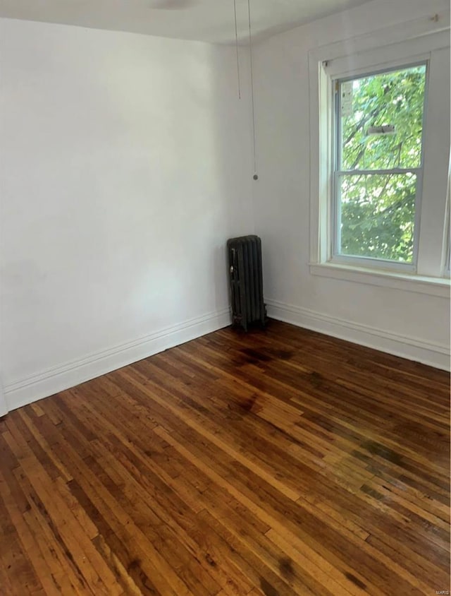 unfurnished room featuring radiator and dark wood-type flooring