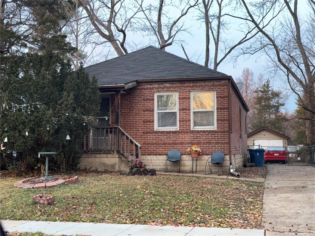 bungalow-style house featuring a garage, an outbuilding, and a front yard