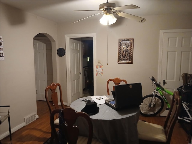 dining area featuring baseboards, visible vents, arched walkways, ceiling fan, and wood finished floors