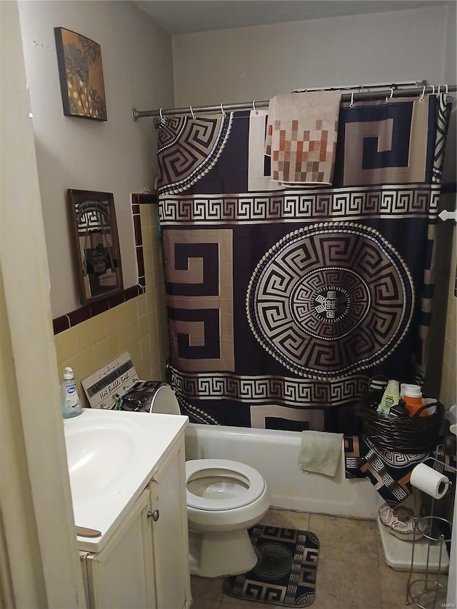 bathroom with shower / tub combo with curtain, tile walls, toilet, vanity, and tile patterned flooring