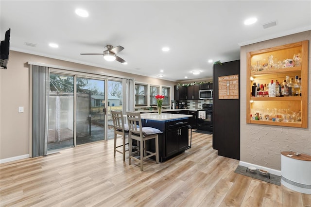 kitchen with a kitchen bar, electric stove, a kitchen island, and light hardwood / wood-style floors