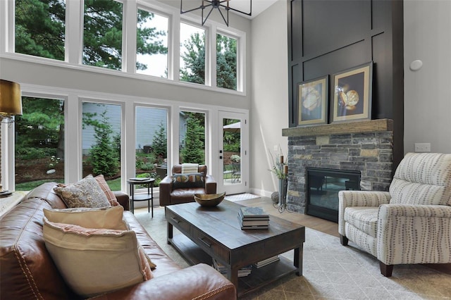 living room featuring a fireplace, a towering ceiling, an inviting chandelier, and a wealth of natural light