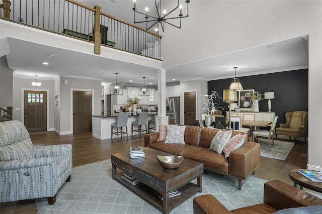 living room featuring hardwood / wood-style flooring, ornate columns, ornamental molding, and a notable chandelier