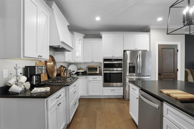 kitchen featuring hanging light fixtures, dark hardwood / wood-style floors, white cabinets, custom range hood, and appliances with stainless steel finishes