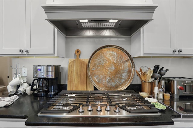 interior details featuring white cabinetry, range hood, and stainless steel gas stovetop