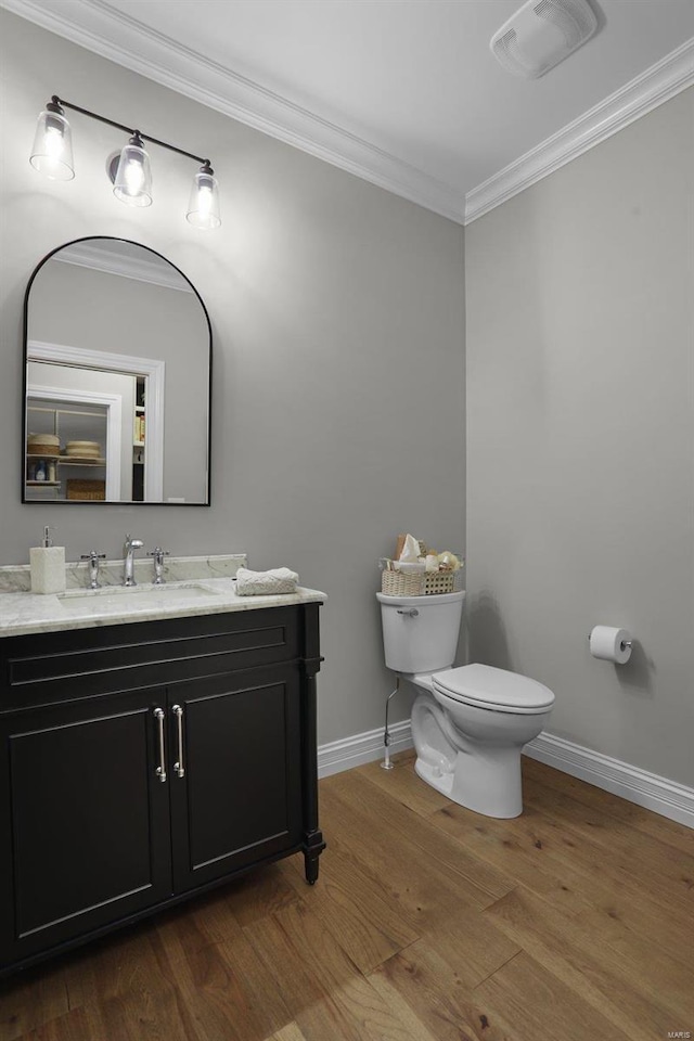 bathroom featuring wood-type flooring, vanity, toilet, and ornamental molding