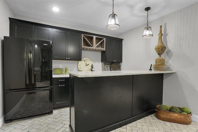 kitchen featuring black refrigerator, sink, kitchen peninsula, and hanging light fixtures