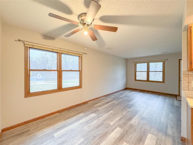 unfurnished living room with ceiling fan, light wood-type flooring, and a textured ceiling