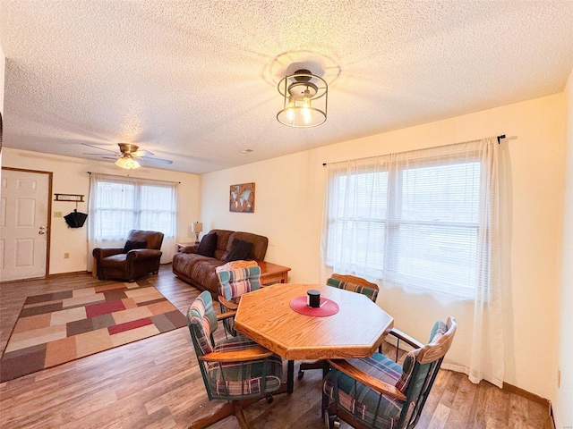 dining area with hardwood / wood-style flooring, ceiling fan, and a textured ceiling