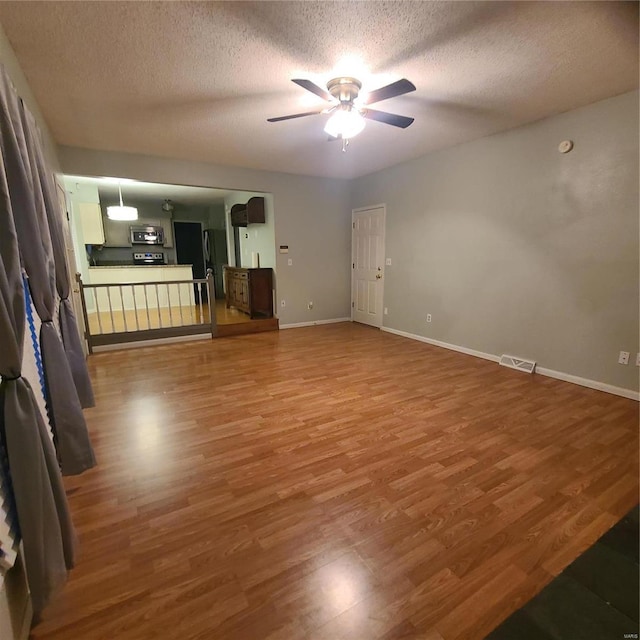 unfurnished living room with wood-type flooring, a textured ceiling, and ceiling fan