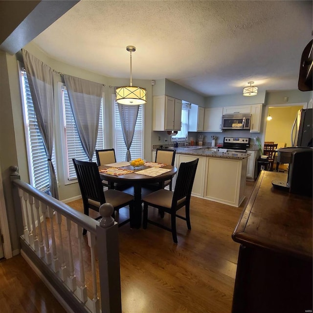 dining room featuring a textured ceiling and dark hardwood / wood-style floors