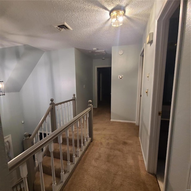 hall featuring lofted ceiling, carpet, and a textured ceiling