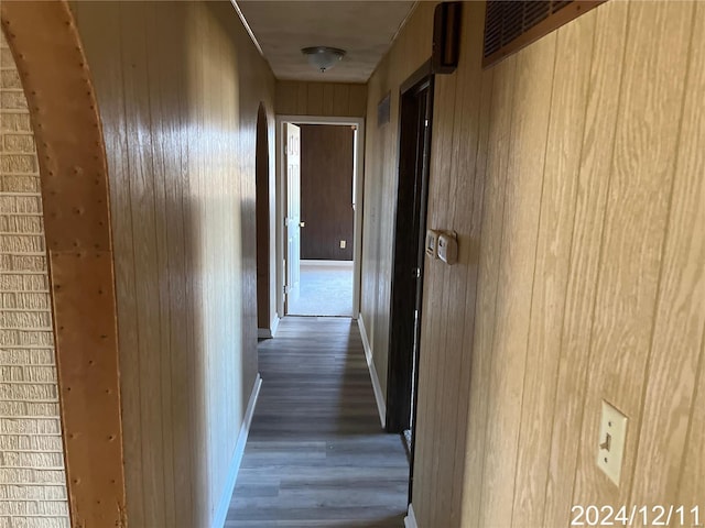 hall with dark wood-type flooring and wooden walls