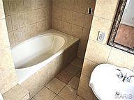 bathroom featuring tile patterned floors, a relaxing tiled tub, and tile walls