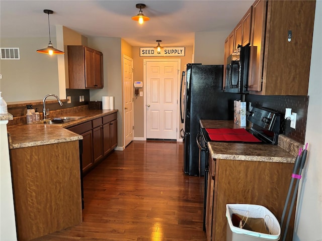 kitchen with decorative light fixtures, sink, dark hardwood / wood-style flooring, and black appliances