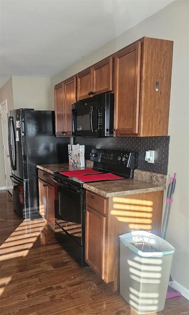 kitchen featuring dark hardwood / wood-style flooring, decorative backsplash, and black appliances