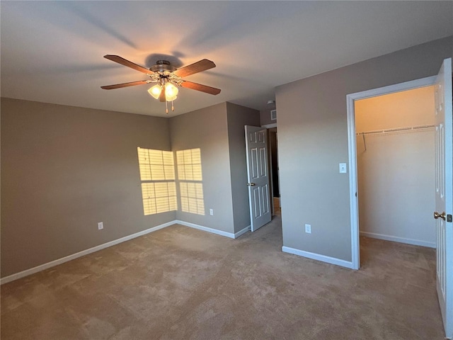 unfurnished bedroom featuring ceiling fan, light colored carpet, a closet, and a walk in closet