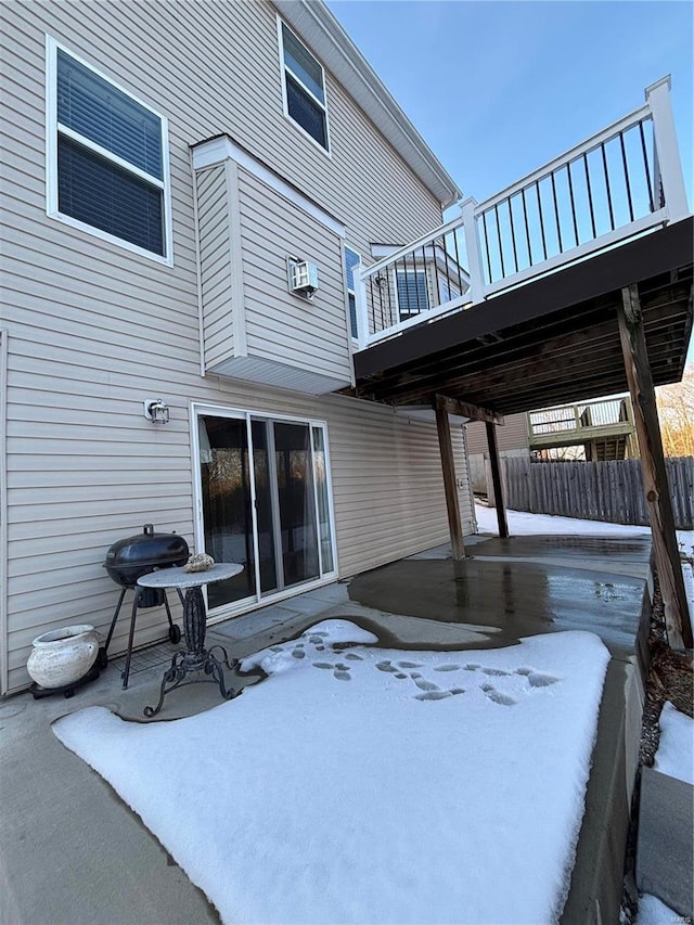 snow covered patio with an AC wall unit, a deck, and grilling area