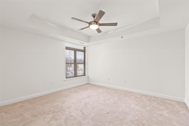 carpeted empty room featuring a tray ceiling and ceiling fan