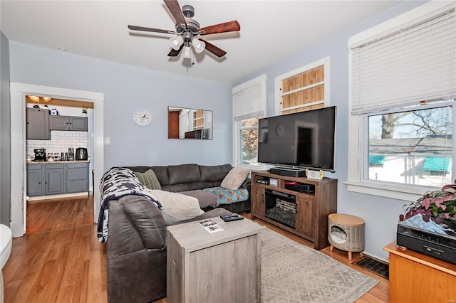 living room featuring light hardwood / wood-style flooring, ceiling fan, and a healthy amount of sunlight