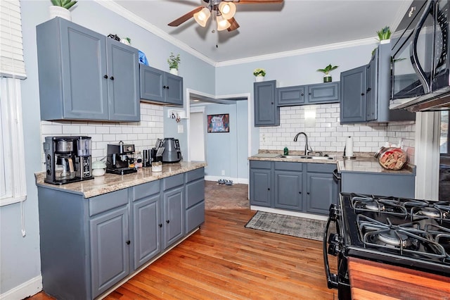 kitchen with sink, backsplash, crown molding, and black appliances