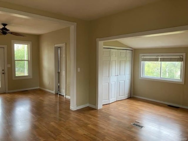 unfurnished bedroom with ceiling fan, light wood-type flooring, multiple windows, and a closet